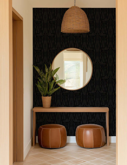 Foyer with round mirror, potted plant, and leather stools against a black textured wall.